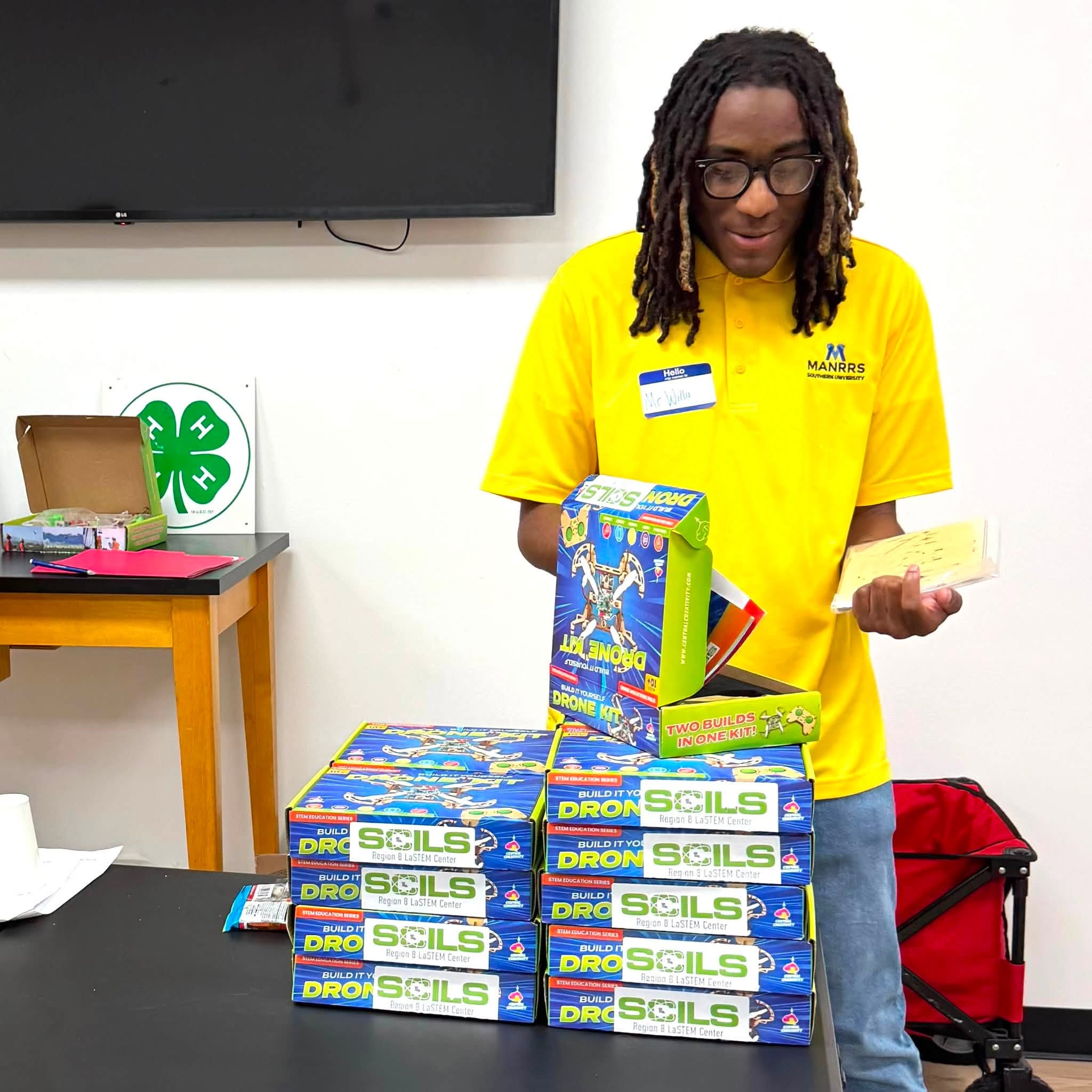 A man standing by a small stack of build-it-yourself drone kits.